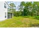 Backyard featuring a well-maintained lawn, mature trees, and a screened-in porch for outdoor relaxation at 4205 Quail Ranch Rd, New Smyrna Beach, FL 32168