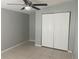 Bright bedroom features tile floors, a closet with folding doors, ceiling fan, and a neutral color palette at 1110 Deltona Blvd, Deltona, FL 32725