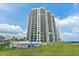 Exterior view of a beachfront condo building with blue skies, a pool, and lawn at 2555 S Atlantic Ave # 207, Daytona Beach Shores, FL 32118