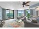Open living room with many windows, light gray modern furniture, and sliding glass doors to a balcony at 2555 S Atlantic Ave # 207, Daytona Beach Shores, FL 32118