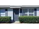 Close up front exterior of a well kept home with blue painted shutters, green hedges and a gray front door at 250 Hickory Ave, Orange City, FL 32763