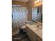 Cozy bathroom features a marble vanity top, patterned shower curtain, and wood look floors at 1461 N Felton St, Deltona, FL 32725