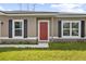 Inviting home featuring a red front door, complemented by black shutters and a well-maintained lawn at 2126 7Th Ave, Deland, FL 32724