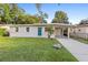 Charming single-story home featuring a well-maintained lawn, a vibrant blue door, and a covered parking area at 522 Powers Ave, Port Orange, FL 32127