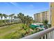 Balcony view showcasing the pool, tropical landscaping, and distant ocean views at 4650 Links Village Dr # C303, Ponce Inlet, FL 32127