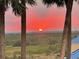 Scenic view of a beautiful orange and red sunset through palm trees overlooking scenic green space at 4650 Links Village Dr # C303, Ponce Inlet, FL 32127