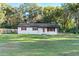 White single story house with red accents, spacious yard, and mature trees at 2 Poinsettia Dr, Deland, FL 32724