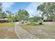 Landscaped backyard featuring a stone pathway, mature trees, and outdoor seating areas at 714 E Michigan Ave, Deland, FL 32724