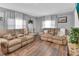 Cozy living room features two tan sofas, wood floors, and soft natural light from the large windows at 714 E Michigan Ave, Deland, FL 32724