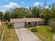 Aerial view of a cozy brick house with an attached garage, driveway, and green lawn at 1639 Templewood Ave, Deltona, FL 32725