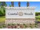 Coastal Woods community entrance sign is surrounded by a stone base with flowers and greenery adding a welcoming touch at 2924 Taton Trce, New Smyrna Beach, FL 32168