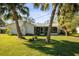 Charming home with a screened-in porch, lush lawn, and white exterior, surrounded by tropical palm trees and green foliage at 1437 Colin Kelly Ave, Daytona Beach, FL 32124