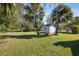 Well-manicured backyard with a storage shed, lush green grass, and mature trees, offering a peaceful outdoor space at 1437 Colin Kelly Ave, Daytona Beach, FL 32124