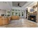 Cozy living room featuring a stone fireplace, a large window with outdoor views, and comfortable leather seating at 227 N Putnam Grove Rd, Oak Hill, FL 32759