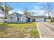 Newly painted home with gray and blue accents, a long driveway, and a well-maintained lawn at 1275 Elkcam Blvd, Deltona, FL 32725