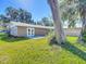 Rear view of the house with a patio and large tree at 2129 Lime Tree Dr, Edgewater, FL 32141