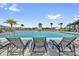 Relaxing community pool area with lounge chairs overlooking the sparkling water with palm trees and neighborhood views at 635 Belgrove St, Debary, FL 32713
