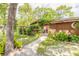 Charming home entrance with a trellised gate, lush greenery, and a stone pathway leading to the front door at 115 Cypress Pond Rd, Port Orange, FL 32128