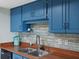 Kitchen with blue cabinets, wood countertops, and double sink at 1513 Ocean Shore Blvd # 2B, Ormond Beach, FL 32176