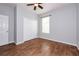 Neutral bedroom with wood tile floor, white double door closet, ceiling fan, and a window at 189 Perfect Dr, Daytona Beach, FL 32124