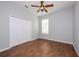 Neutral bedroom with wood tile floor, white double door closet, ceiling fan, and a window at 189 Perfect Dr, Daytona Beach, FL 32124