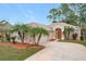 Tan house with palm trees, a two-car garage, and a manicured lawn at 189 Perfect Dr, Daytona Beach, FL 32124