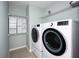 Functional laundry room with modern washer and dryer, storage cabinets, and shelving at 189 Perfect Dr, Daytona Beach, FL 32124
