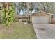Tan single-story house with attached garage and mature landscaping at 2125 Queen Palm Dr, Edgewater, FL 32141