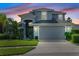 Two-story house with gray exterior, two-car garage, and landscaped yard at dusk at 5423 Swordfern Ct, Port Orange, FL 32128