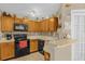 Galley kitchen with wood cabinets and black appliances at 963 Helmsley Ct # 207, Lake Mary, FL 32746