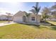 Tan house with white garage door, landscaping, and palm trees at 981 Wilmington Dr, Deltona, FL 32725