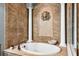 Luxurious bathroom featuring a soaking tub with tile surround, columns, and decorative sconce at 3548 Tuscany Reserve Blvd, New Smyrna Beach, FL 32168