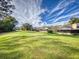 The screened lanais are featured from the backyard with lush, green grass and professional landscaping at 55 Fairway Dr # 3D, Debary, FL 32713