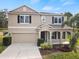 Tan two-story house with black shutters, a two-car garage, and a landscaped yard at 10025 Scottish Pines Ct, Orlando, FL 32832