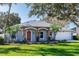 Single-story home with stone accents, red door, and landscaped lawn at 12 Peruvian Ln, Ormond Beach, FL 32174