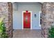 Red front door entryway with stone columns and tile flooring at 12 Peruvian Ln, Ormond Beach, FL 32174