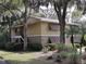Tan two-story building with brown roof and shutters, nestled among lush greenery at 130 Jasmine Woods Ct # 15C, Deltona, FL 32725