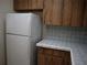 White refrigerator with wood cabinets and light gray countertops at 130 Jasmine Woods Ct # 15C, Deltona, FL 32725