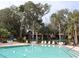 Community pool with lounge chairs and umbrellas, surrounded by palm trees at 130 Jasmine Woods Ct # 15C, Deltona, FL 32725