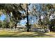 View of backyard with a white fence, large trees, and lush green lawn at 1900 Knolton Ave, Orange City, FL 32763