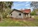 Side view of a single-story home featuring wood siding, a brick foundation, and a red roof, nestled among lush trees at 2170 Wilmhurst Rd, Deland, FL 32720