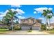 Inviting two-story home featuring a three-car garage, well-maintained landscaping, and a sunny blue sky at 310 La Creek Ct, Debary, FL 32713