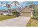 Tan house with palm trees, landscaped lawn, and two-car garage at 34 Black Creek Way, Ormond Beach, FL 32174