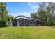 Spacious backyard with a screened enclosure, lush green grass, mature trees, and space for outdoor enjoyment at 39 Ormond Green Blvd, Ormond Beach, FL 32174