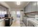 Kitchen with gray cabinets, white appliances, and tiled floors at 469 S Halifax Dr, Ormond Beach, FL 32176