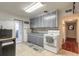 Galley kitchen, gray cabinets, white appliances, and tiled floor at 469 S Halifax Dr, Ormond Beach, FL 32176