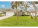 Tan house with white garage door, lush green lawn, and mature palm trees at 123 Ponce Terrace Cir, Ponce Inlet, FL 32127