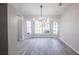 Bright dining area featuring a modern chandelier, light gray plank flooring, and large windows offering ample natural light at 130 Old Sunbeam Dr, South Daytona, FL 32119