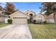 Tan house with a two-car garage and a well-maintained lawn at 3125 Wood Rose Way, Deltona, FL 32725