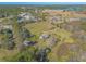 Aerial view showcasing a house nestled in a vast green field with surrounding trees and distant water at 601 Rasley Rd, New Smyrna Beach, FL 32168